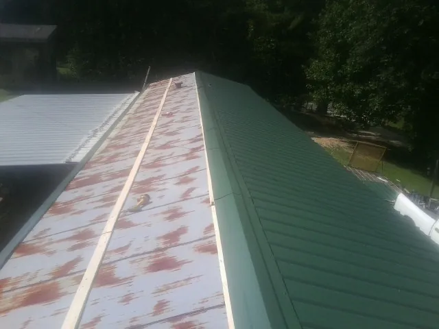 Old rusted panels beside newly installed green metal roofing — Wind Damage Roof Repair by Roofing Brothers in North Stonington