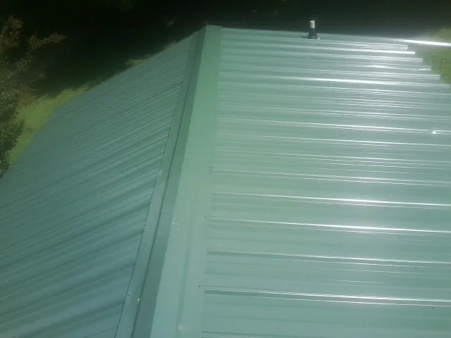 New green metal panels meeting at the ridge of a roof — Flat Roof Repair work by our crew in North Stonington