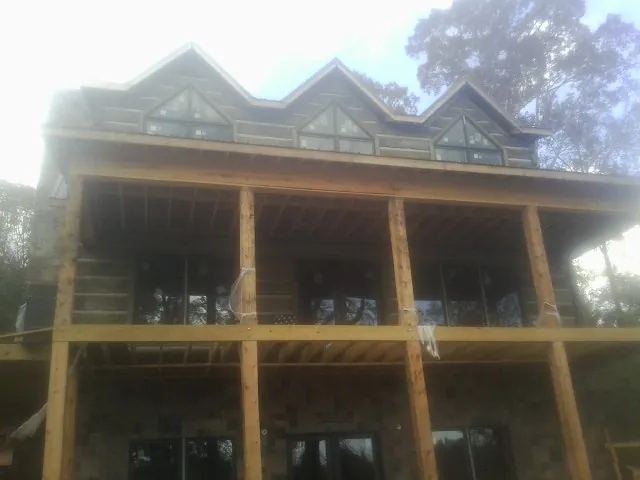 Dormers and porch framing on a large log home under construction — Roof Coating work by our crew in North Stonington