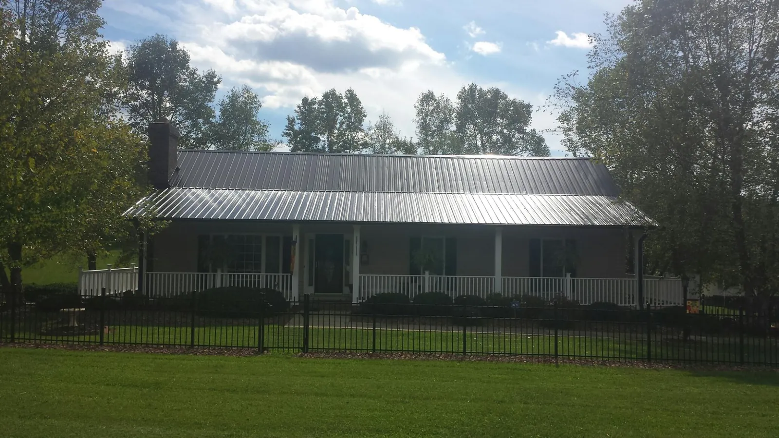Gray metal roof on a brick ranch with a full width front porch — Gutter Guard Installation work by our crew in North Stonington