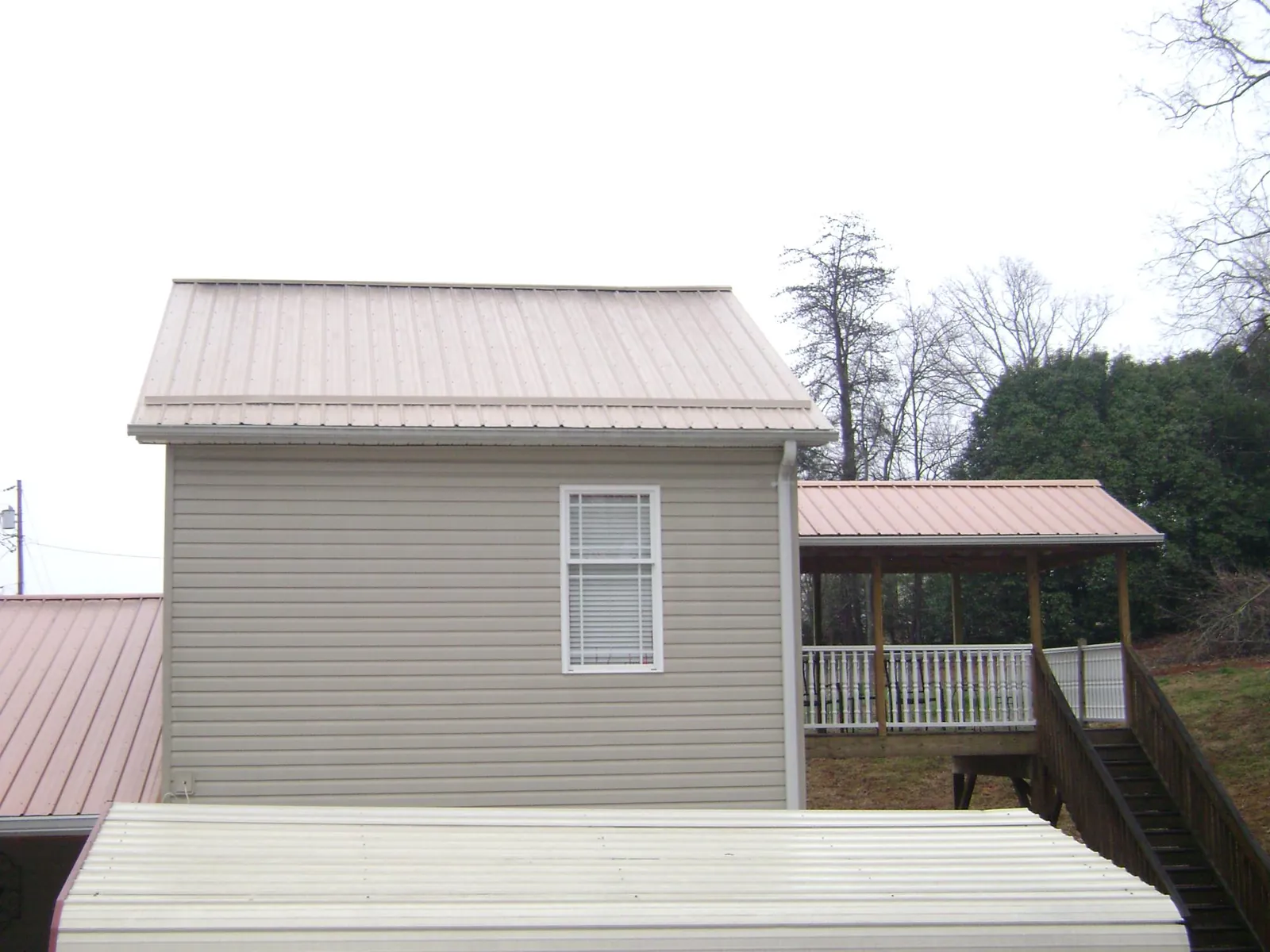 Tan metal roofs on a two story addition and attached porch, from a Roof Replacement job in North Stonington