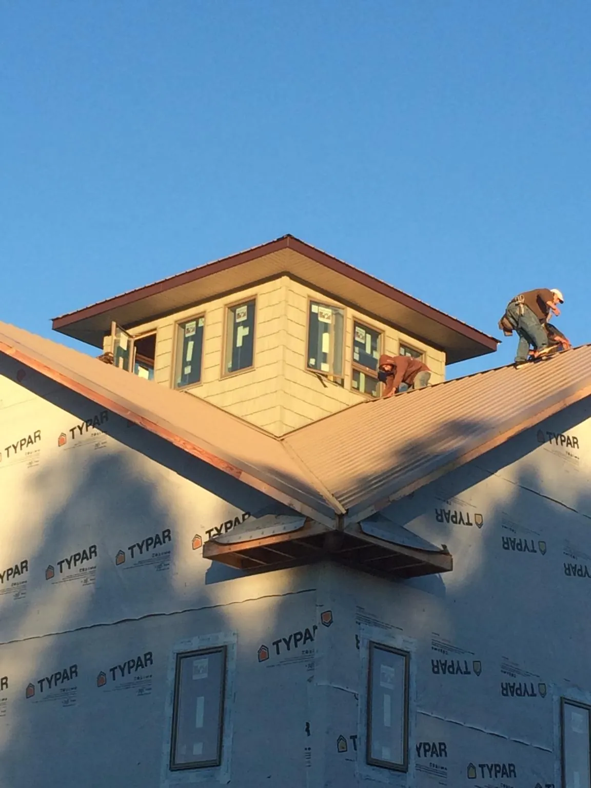 Roofers working around a rooftop cupola on a new metal roof at sunset — Roof Waterproofing in North Stonington by Roofing Brothers